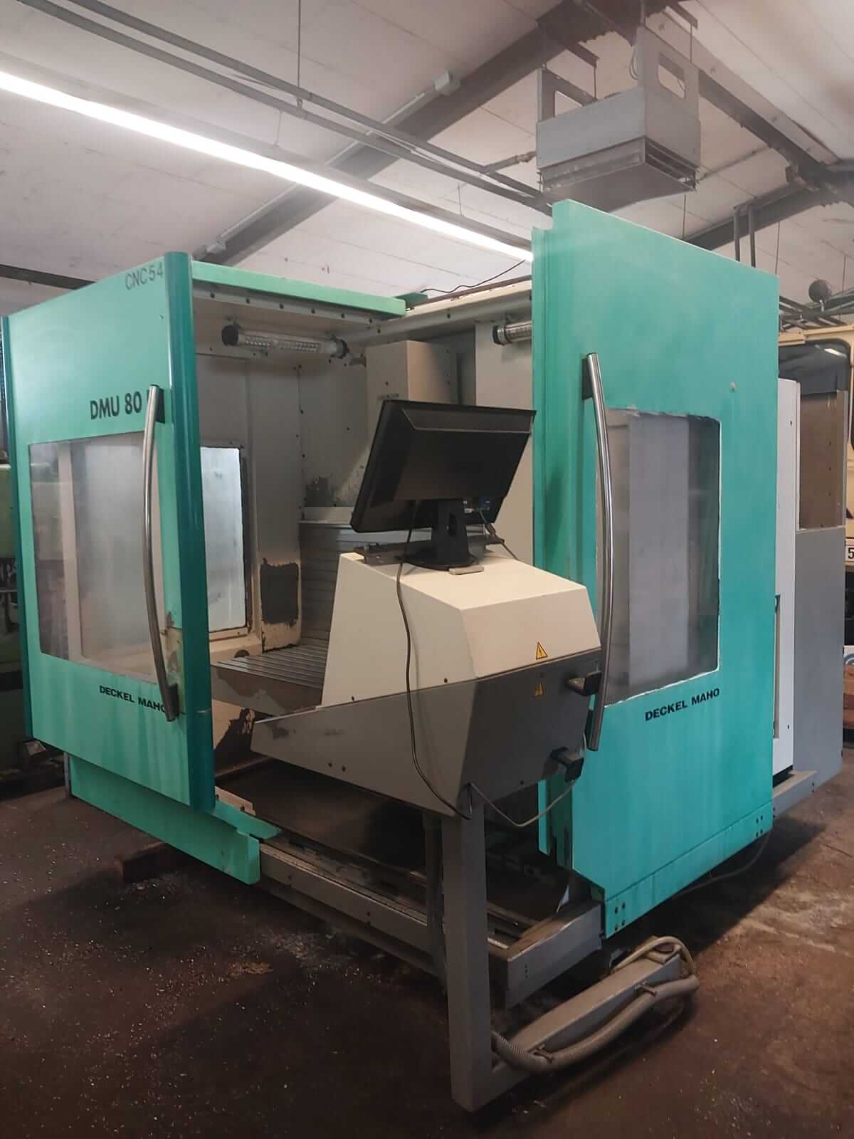 Eine grüne CNC-Fräsmaschine DMU 80 der Marke Deckel Maho steht in einer industriellen Werkstattumgebung.