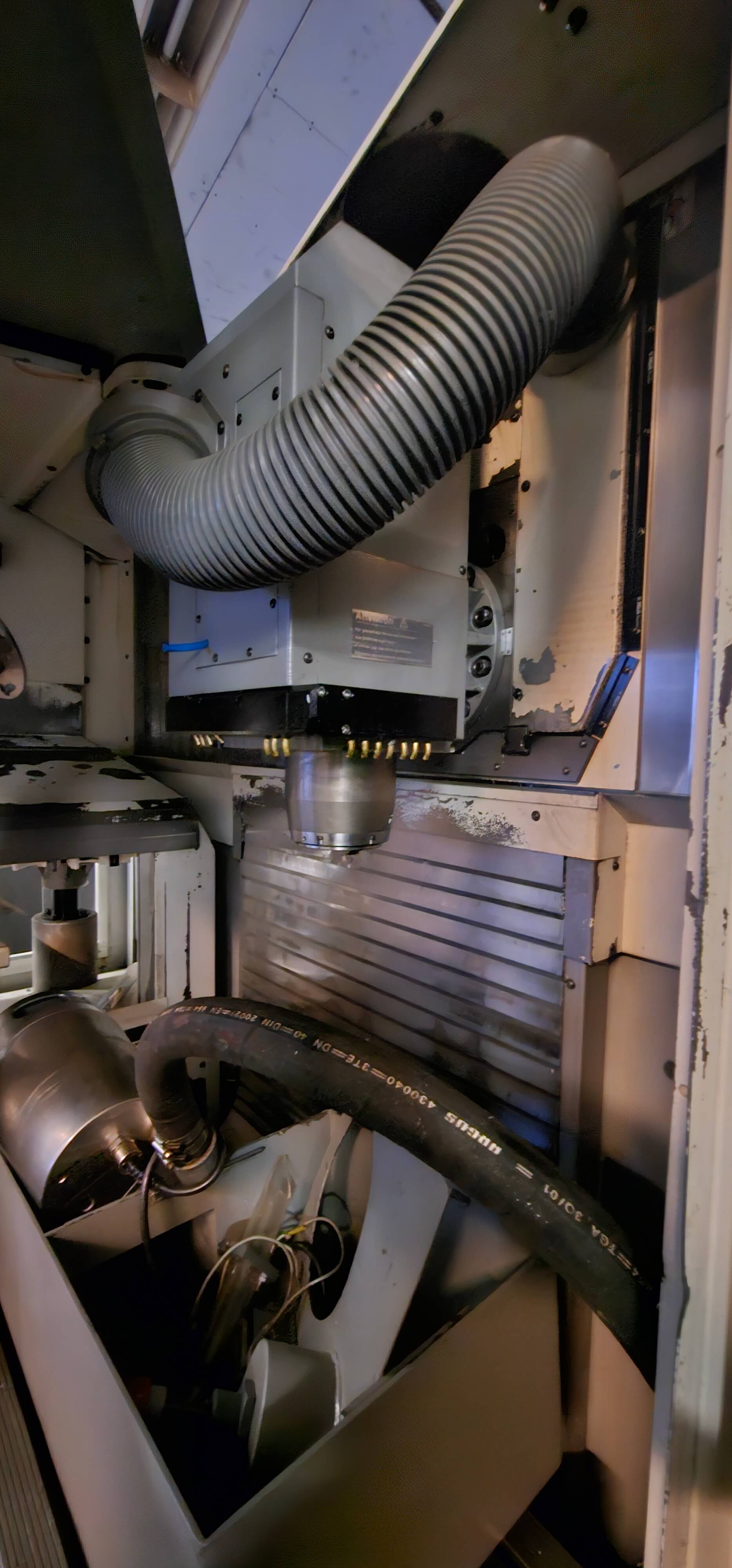 Innenansicht einer CNC-Fräsmaschine mit erkennbaren Belüftungsschläuchen und Metallkomponenten.